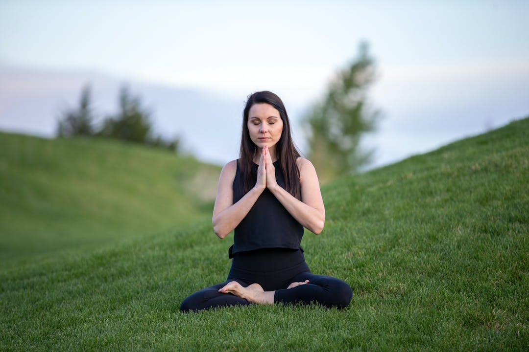 kvinde der mediterer på en græsplæne